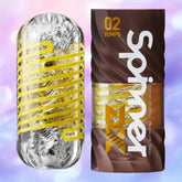 A clear cylindrical Tenga Spinner DX 02 Bumps male masturbator with a yellow spiral is displayed beside its brown and yellow packaging, against a soft pastel background, showcasing spin-powered pleasure from Tenga.